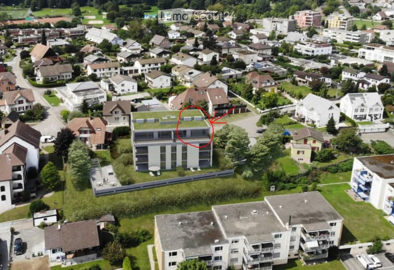 Aerial view of a residential area with multiple houses, green spaces, and a highlighted building with a green roof.