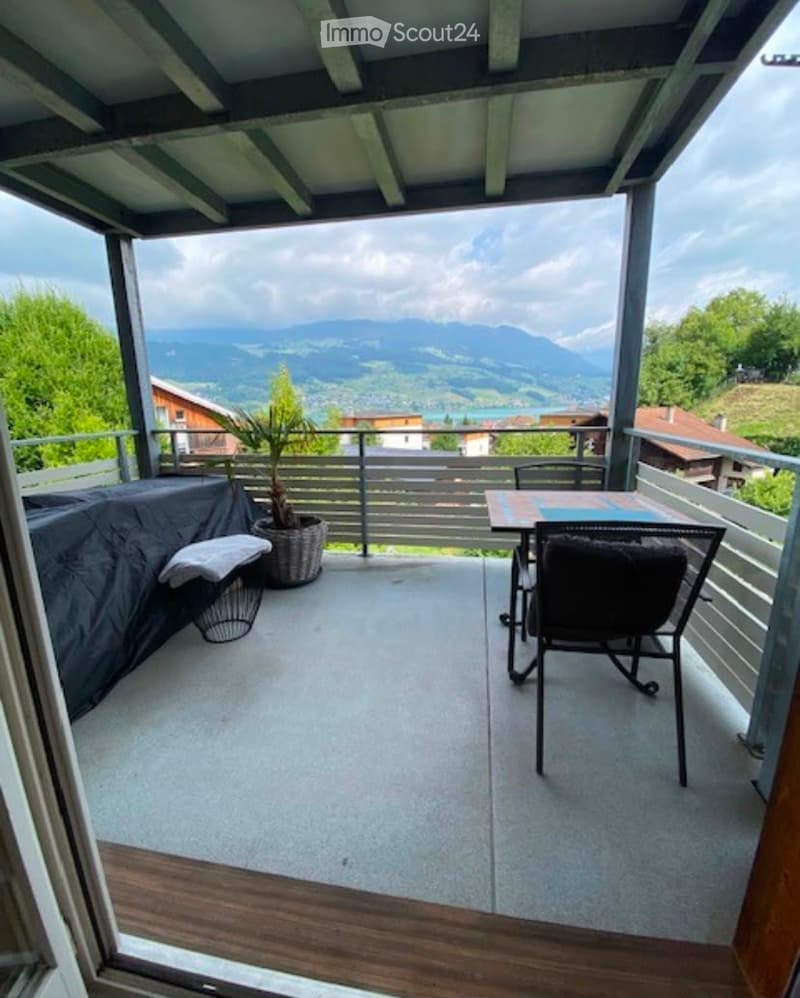 Balcony with a scenic mountain view, featuring a table, chairs, and a potted plant.