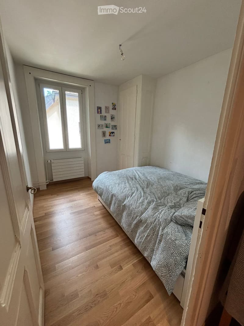Cozy bedroom with wooden flooring, a single bed with patterned bedding, a radiator, and a door leading to a balcony or terrace.