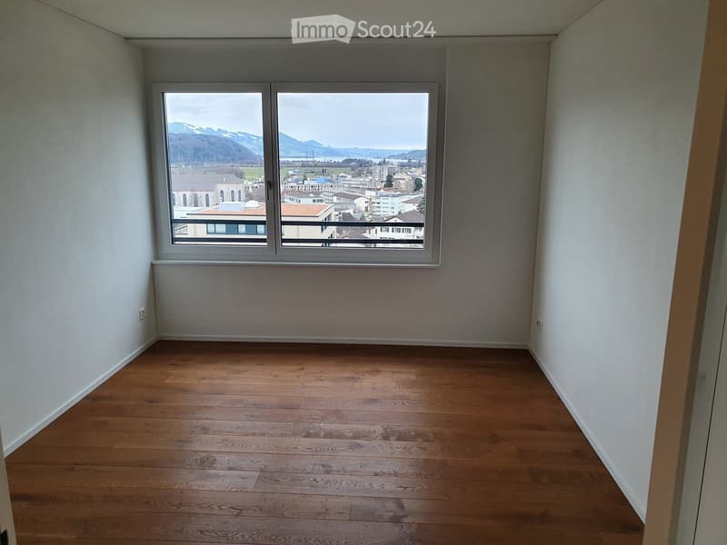 empty room, wooden floor, white walls, large window with city view