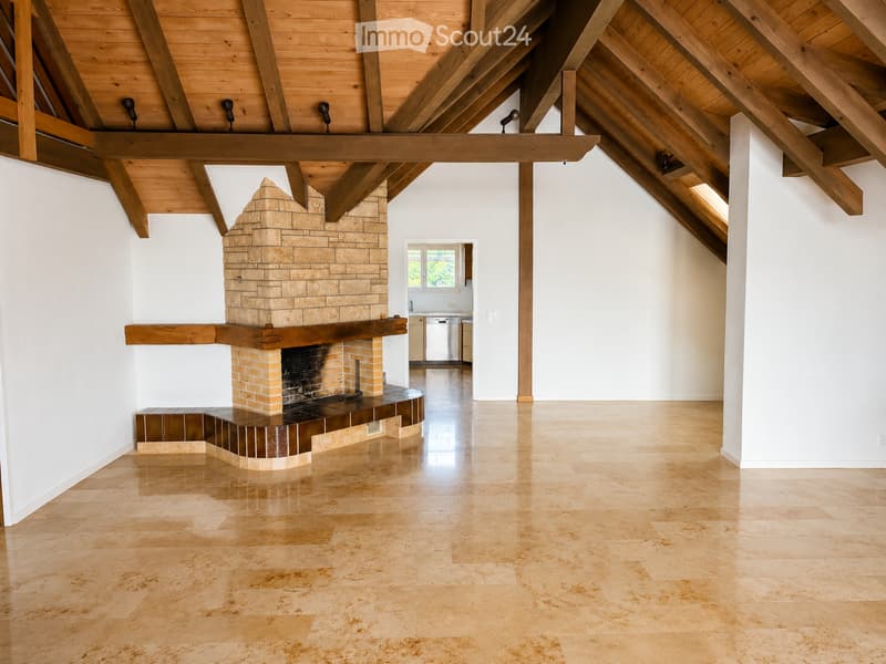 Open-concept living room with exposed wooden beams, a stone fireplace, and polished tile flooring.