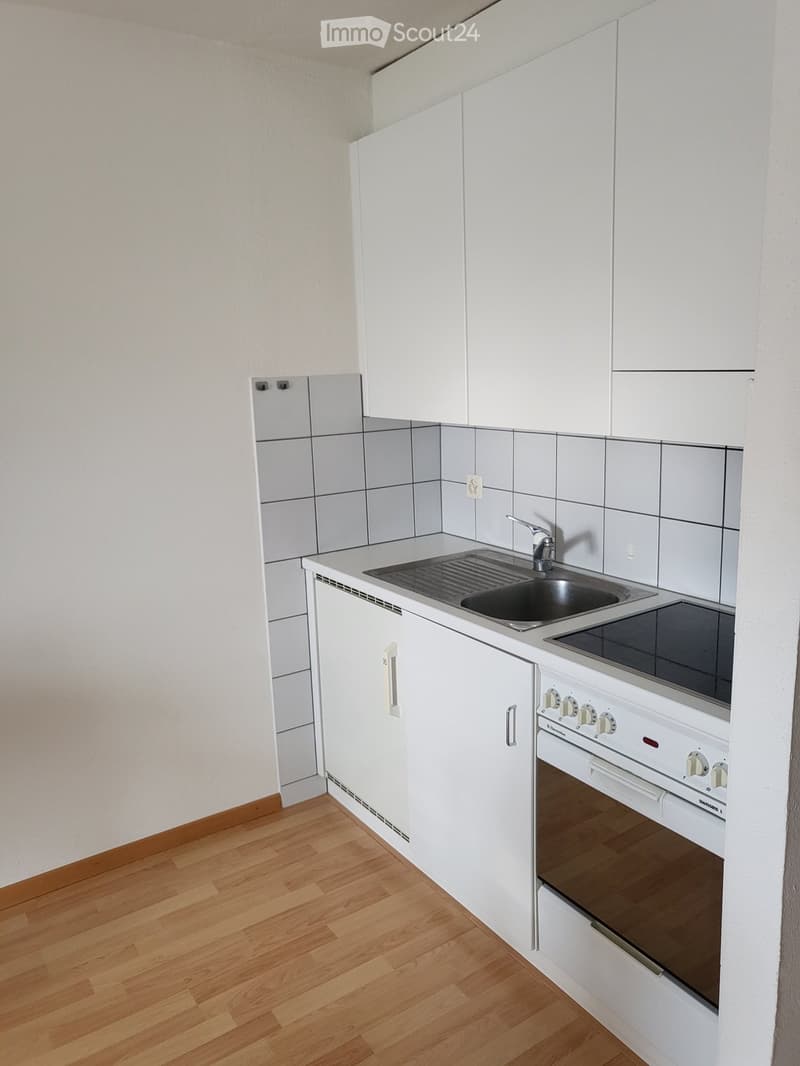 Modern kitchen with white cabinets, wooden flooring, sink, faucet, and oven.