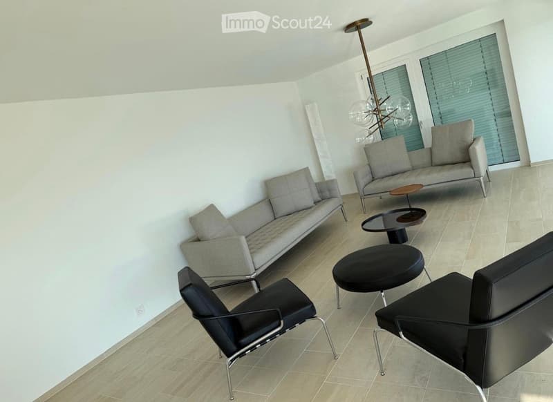 Modern living room with light grey sofa, black chairs, small tables, and a stylish floor lamp.
