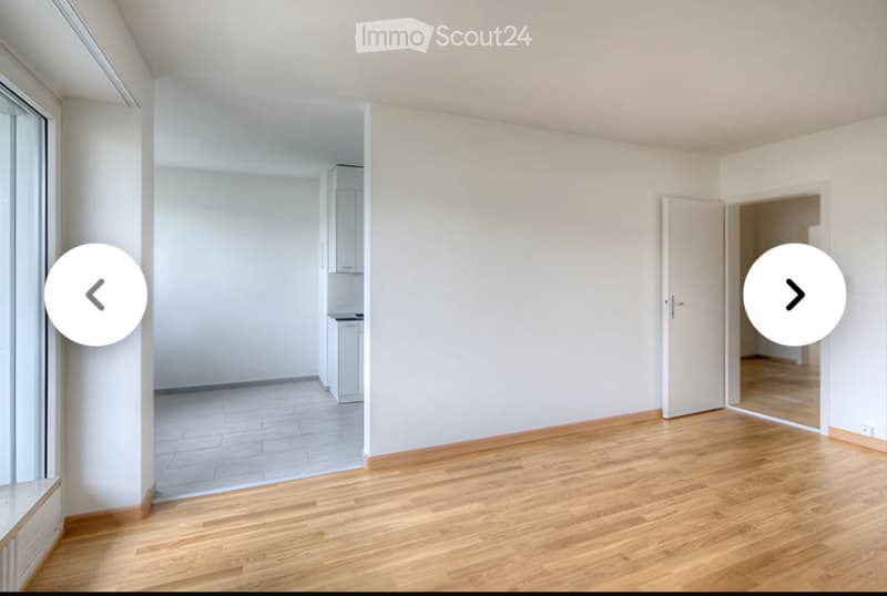 Empty room with wooden flooring, white walls, and large windows. No furniture or equipment present.