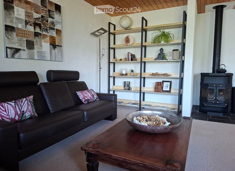 Modern living room with a dark leather sofa, wooden coffee table, floor lamp, bookshelf, and a fireplace.