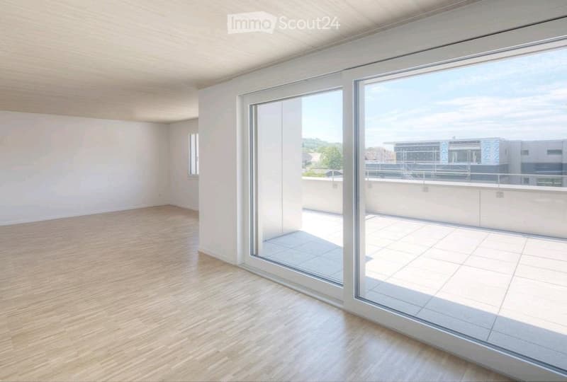 Empty room with wooden flooring, white walls, and large glass sliding doors leading to a balcony area.