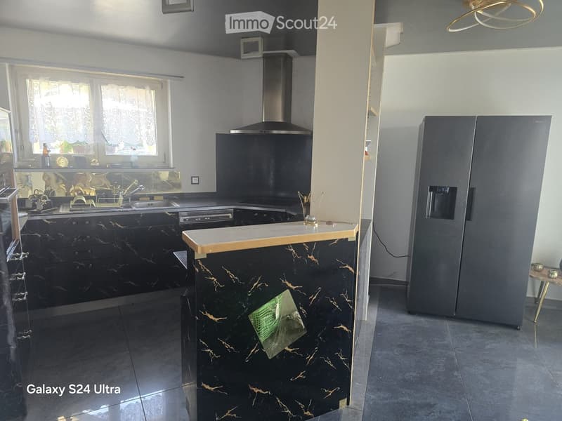 Modern kitchen with black marble cabinets, stainless steel appliances, and a central island with a wooden countertop.