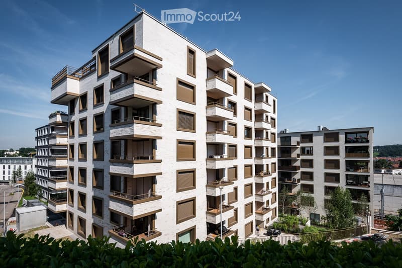 Modern multi-story residential building with balconies, large windows, and contemporary design.