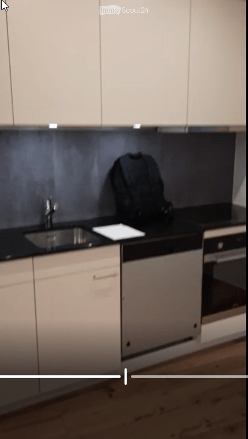 Modern kitchen with white cabinets, black countertops, stainless steel sink, oven, and dishwasher. A backpack is placed on the counter.