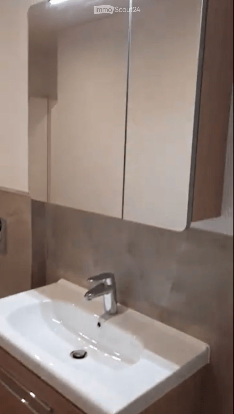 Modern bathroom with a white sink, chrome faucet, and light-colored cabinets.