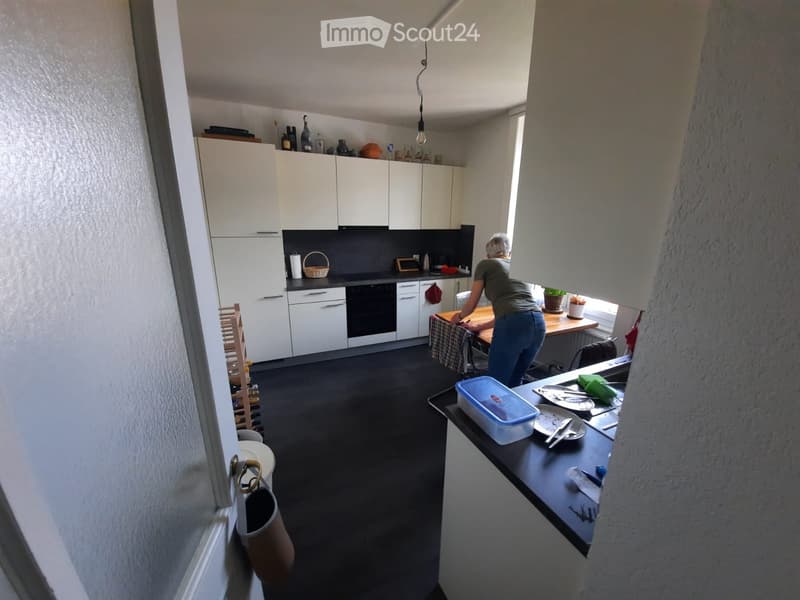 Modern kitchen with white cabinets, black countertops, and stainless steel appliances. Includes a sink, oven, and various kitchen items on the counters.