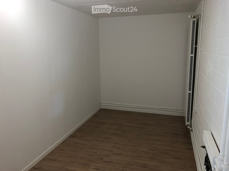 Empty room with wooden flooring, white walls, and a radiator on the right side.