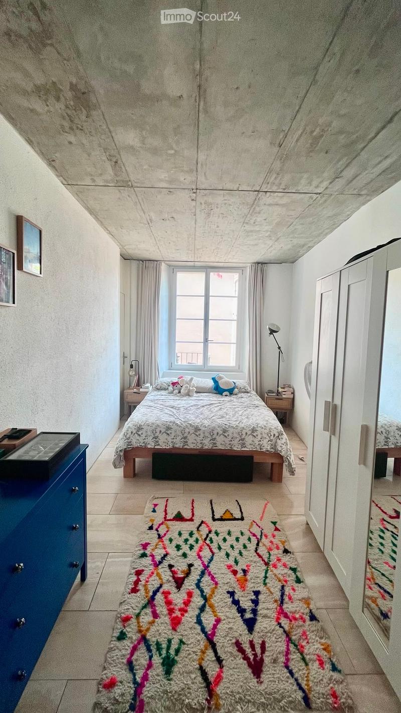 A cozy bedroom with a double bed, nightstands, a colorful rug, and a blue dresser.