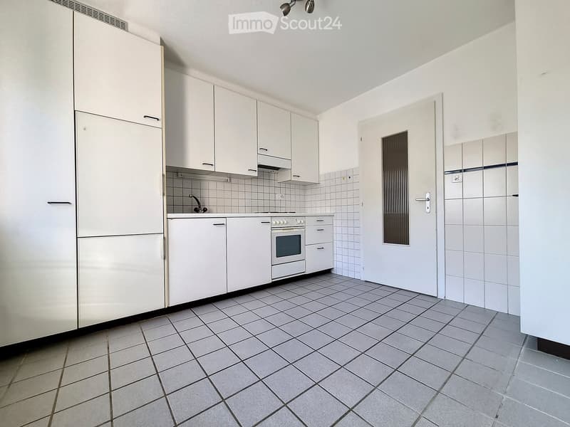 Modern kitchen with white cabinets, a refrigerator, an oven, and a sink, featuring tiled walls and floor.