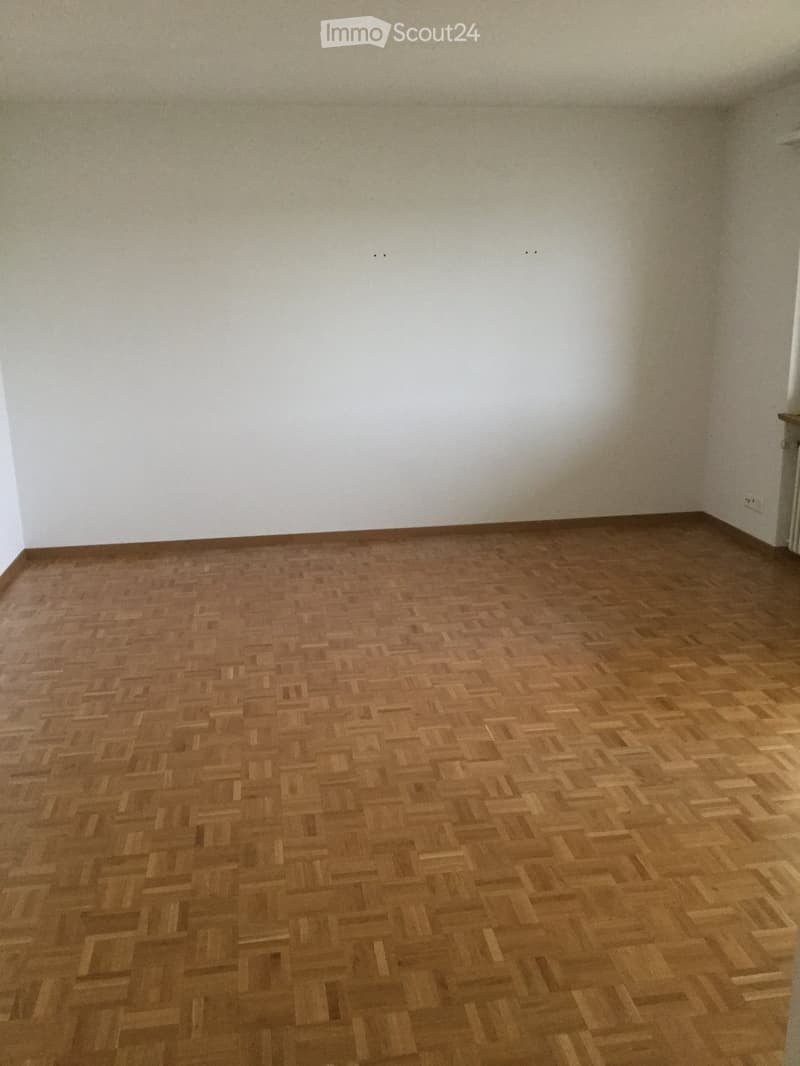 Empty room with wooden herringbone flooring and white walls, no furniture or equipment present.