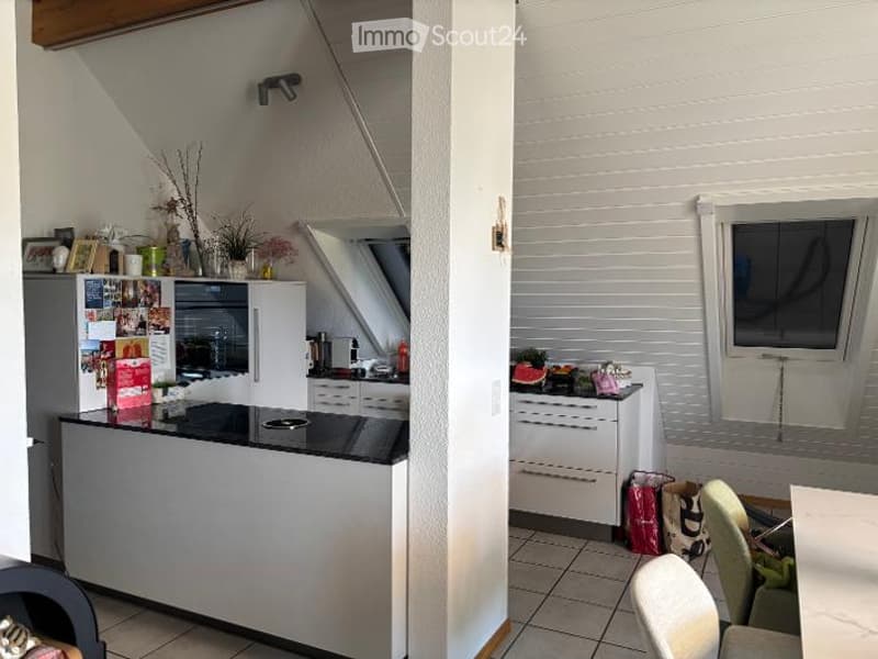 Modern kitchen with white cabinets, black countertop, and stainless steel appliances. Includes a refrigerator, oven, microwave, dishwasher, and a small dining area with a table and chairs.
