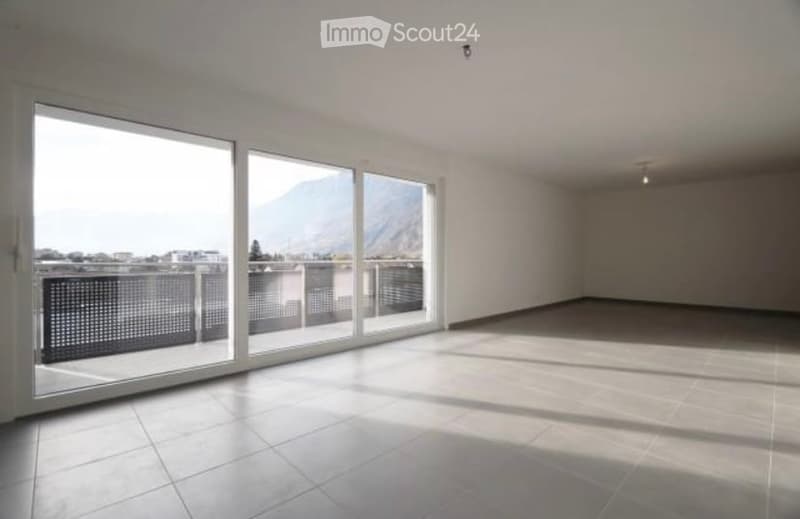 Empty room with large windows offering a scenic mountain view, tiled floor, and modern lighting fixtures.