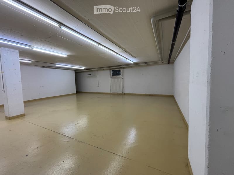 Empty room with white walls, white columns, beige floors, radiator and fluorescent ceiling lights