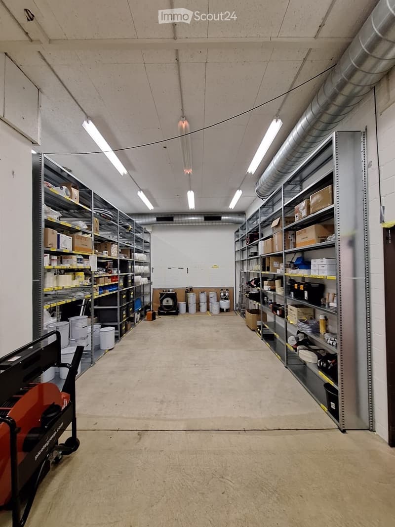 Empty storage room with metal shelving units, industrial flooring, and fluorescent lighting. No furniture or personal items present.