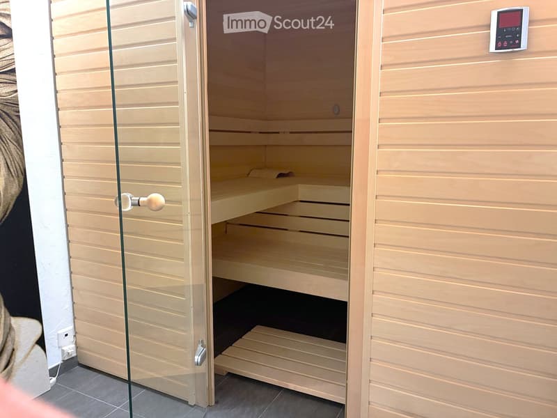 Wooden sauna with multiple benches and a control panel on the wall.