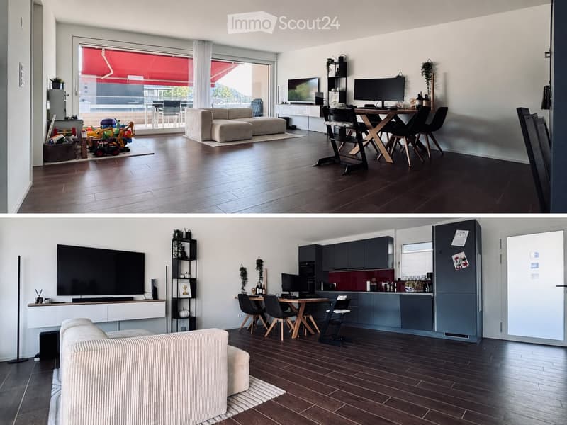 Modern open-plan living and dining area with a sofa, ottoman, dining table, chairs, kitchen cabinets, refrigerator, and television. The space features wooden flooring and large windows with a view.