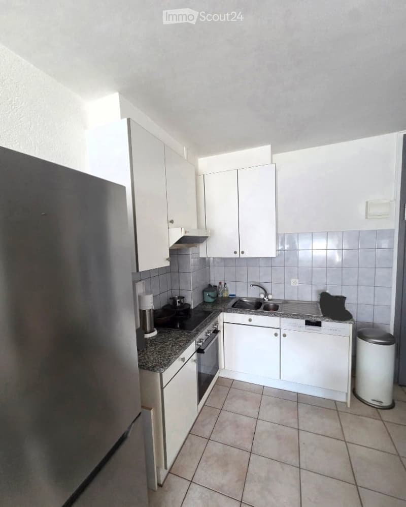 Modern kitchen with white cabinets, granite countertop, stainless steel appliances including a refrigerator, oven, sink, and dishwasher. Features tiled backsplash and tiled flooring.