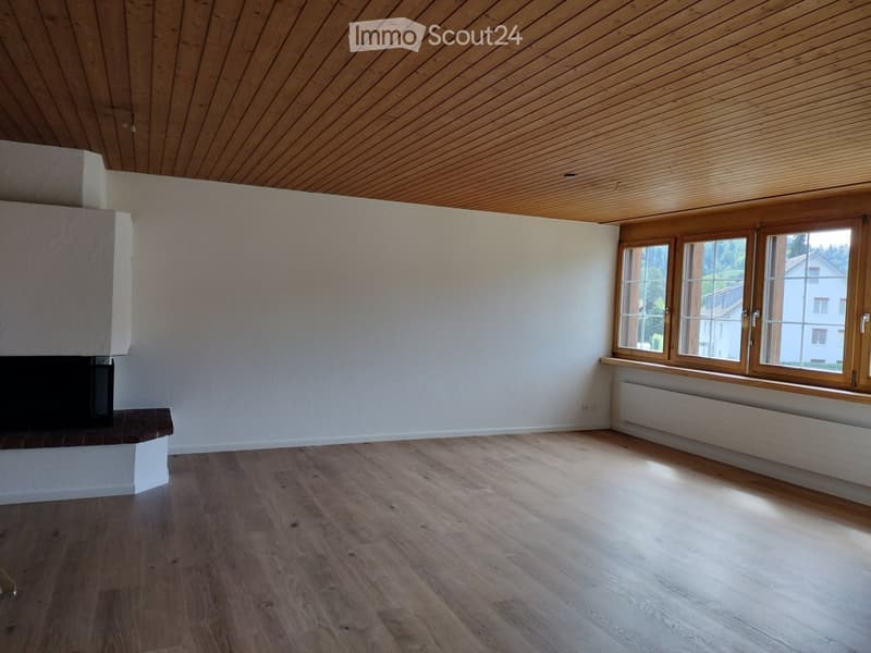 Unfurnished Room. Empty room with wooden flooring, white walls, and a fireplace. Large windows with wooden frames allow natural light to enter.