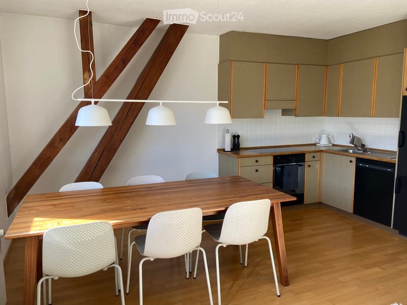 Modern kitchen with wooden table, white chairs, built-in cabinets, and appliances including an oven and dishwasher.