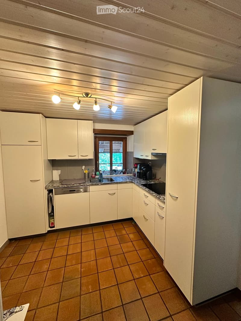 Bright kitchen with white cabinets, granite countertops, and a tiled floor. Features a sink, dishwasher, and coffee maker.