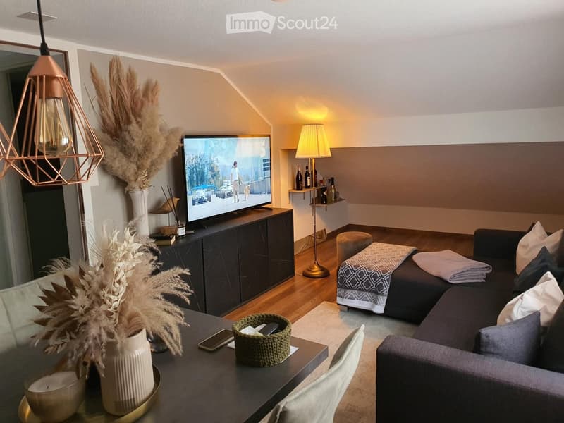 Modern living room with a grey sectional sofa, coffee table, TV, table lamp, decorative vases, and a cozy seating area.