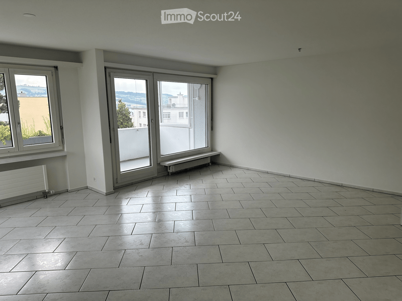 Empty room with tiled floor, large windows, and sliding glass doors leading to a balcony.