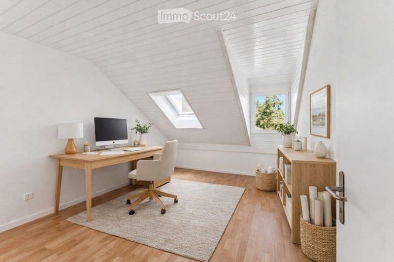 Bright, airy attic office with wooden floors, white paneled walls, large windows, skylights, and a cozy workspace setup.