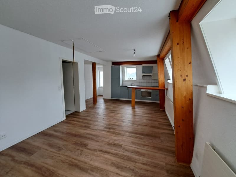 Empty room with wooden flooring, white walls, and visible structural beams. No furniture or equipment present.