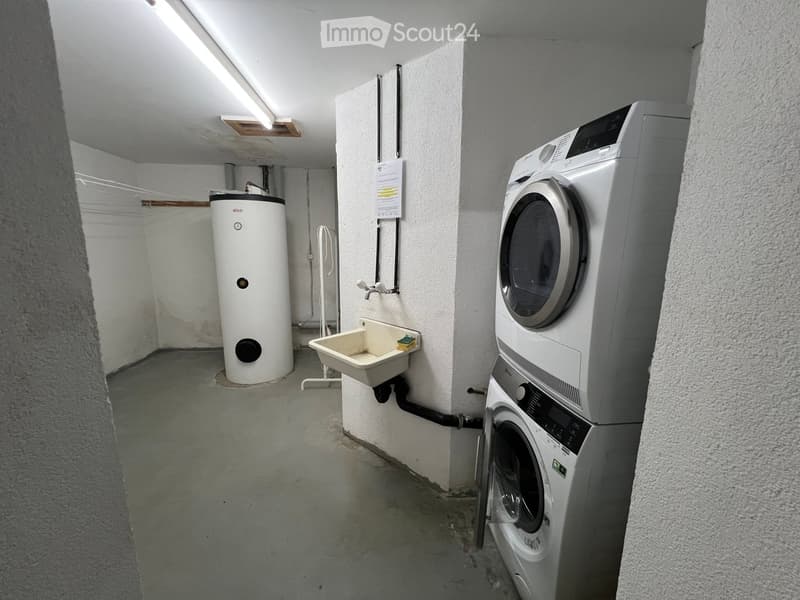 Utility room with a washing machine, dryer, water heater, and a small sink.