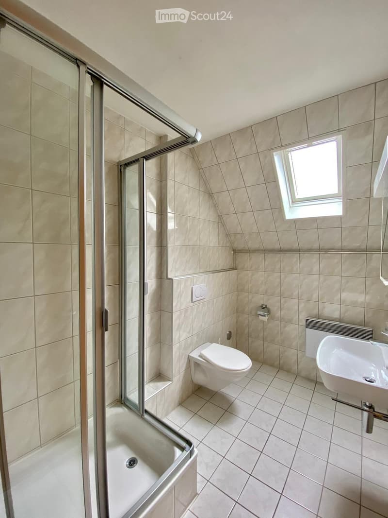 small bathroom with shower, toilet, and sink with window