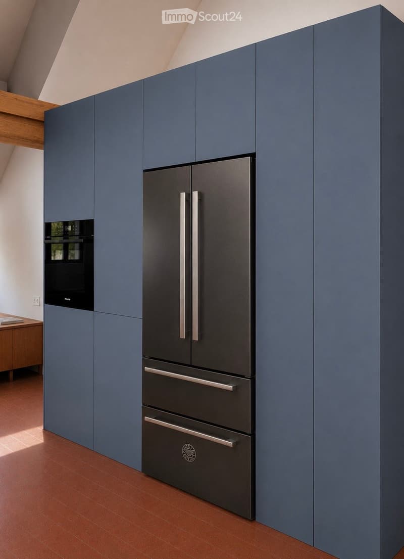 Modern kitchen with blue cabinets, stainless steel refrigerator, and built-in oven. Wooden beams on the ceiling and terracotta flooring.