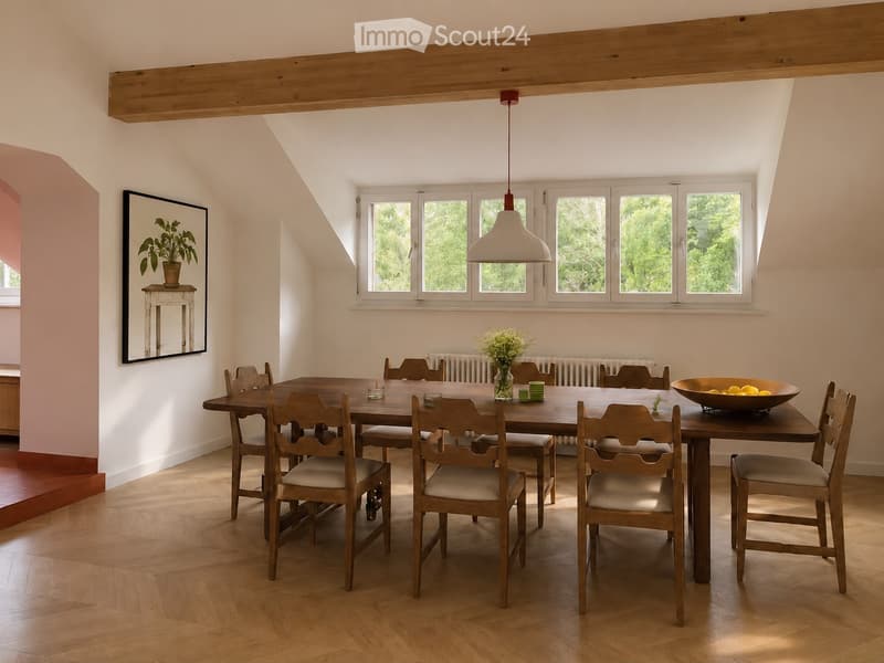 Bright dining room with wooden dining table and chairs, large windows, pendant light, and decorative items including a vase with flowers and a bowl of fruit.