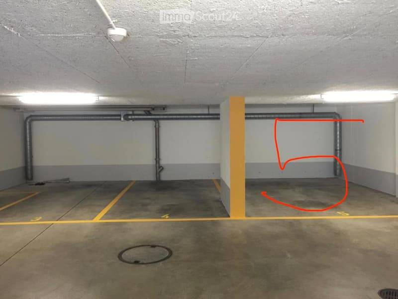 Underground parking space with concrete floors, grey walls, yellow parking lines, and a single marked parking spot outlined in red.
