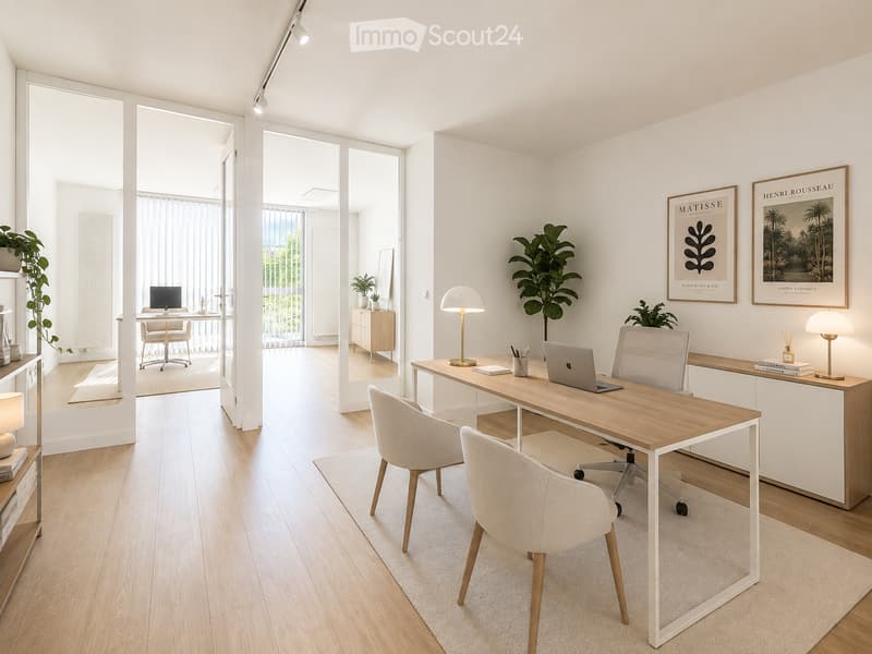Modern, well-lit office space with a large wooden desk, laptop, two chairs, table lamps, plants, and framed artwork on the walls. The room features light wooden flooring and large windows with sheer curtains.
