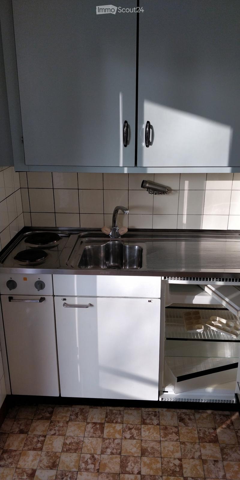 Modern kitchen with white cabinets, stainless steel sink, oven, and dishwasher. Features a tiled backsplash and tiled floor.