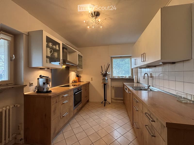 modern kitchen with wooden cabinets, tiled floor, stainless steel appliances, ceiling lamp, sink, faucet, coffee machine, oven, radiators