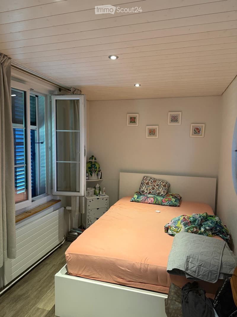 Cozy bedroom with a single bed, colorful bedding, nightstand, and decorative items on the wall.