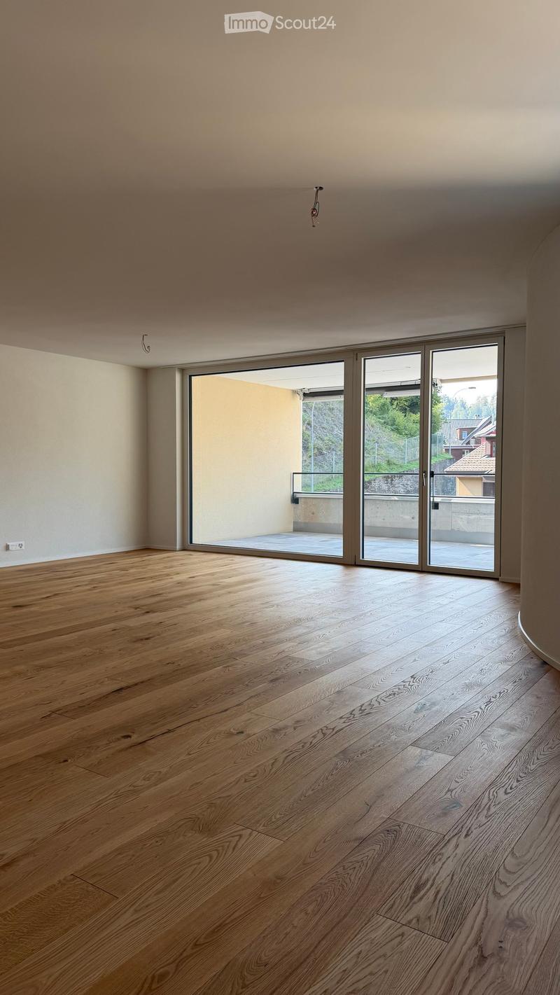 Empty room with light wooden flooring and large glass sliding doors leading to a balcony or outdoor area.