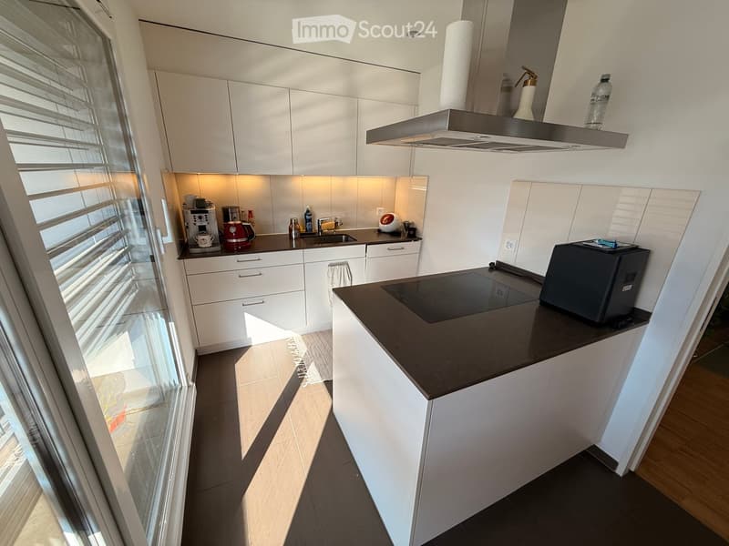 Modern kitchen with white cabinets, dark countertops, and various appliances including a coffee maker, oven, microwave, and sink.