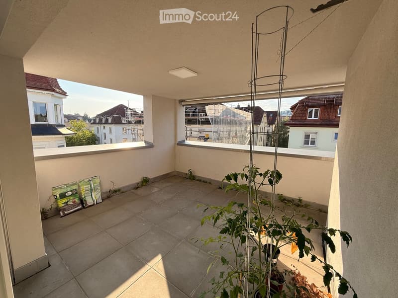 Balcony with tiled floor, potted plants, and bags of fertilizer on the left side.