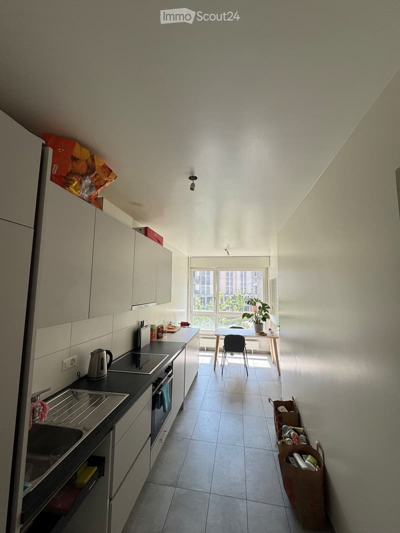 Modern kitchen with white cabinets, stainless steel appliances, and a small dining area with a table and chairs. The kitchen features a stove, oven, sink, and various small appliances.