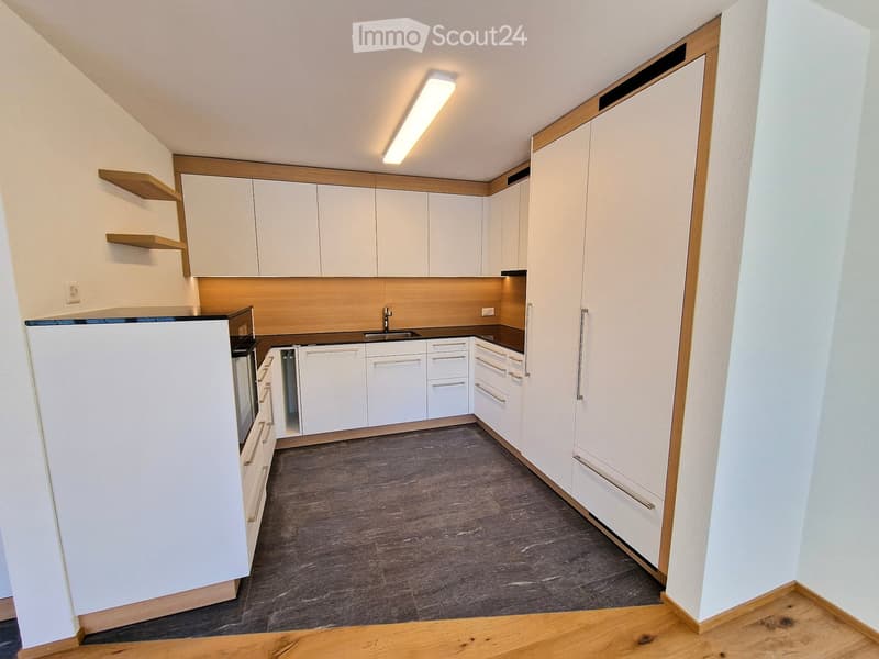 Modern kitchen with white cabinets, a refrigerator, oven, sink, and wooden shelves.