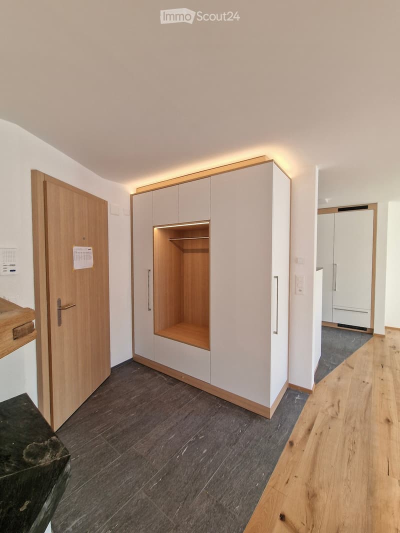 Empty hallway with wooden doors, built-in closet, and light wood flooring. No furniture or personal items visible.