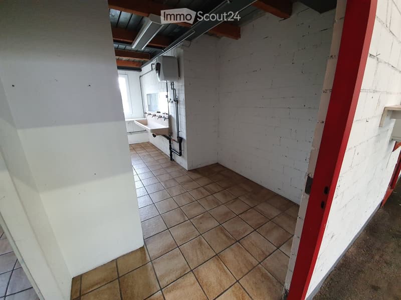 Empty room with tiled floor and white brick walls, featuring a sink and exposed pipes in the background.