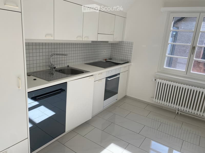 Modern kitchen with white cabinets, tiled backsplash, stainless steel sink, and built-in oven.